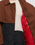 Plan C Quilted Double Breasted Coat. Black quilted culpro and cotton interior with a chestnut brown wool over piece at the collar, sleeves and waist. Highlighted by a wrap around long belt at the waist. This photo shoes the red detailing on the interior of the jacket.