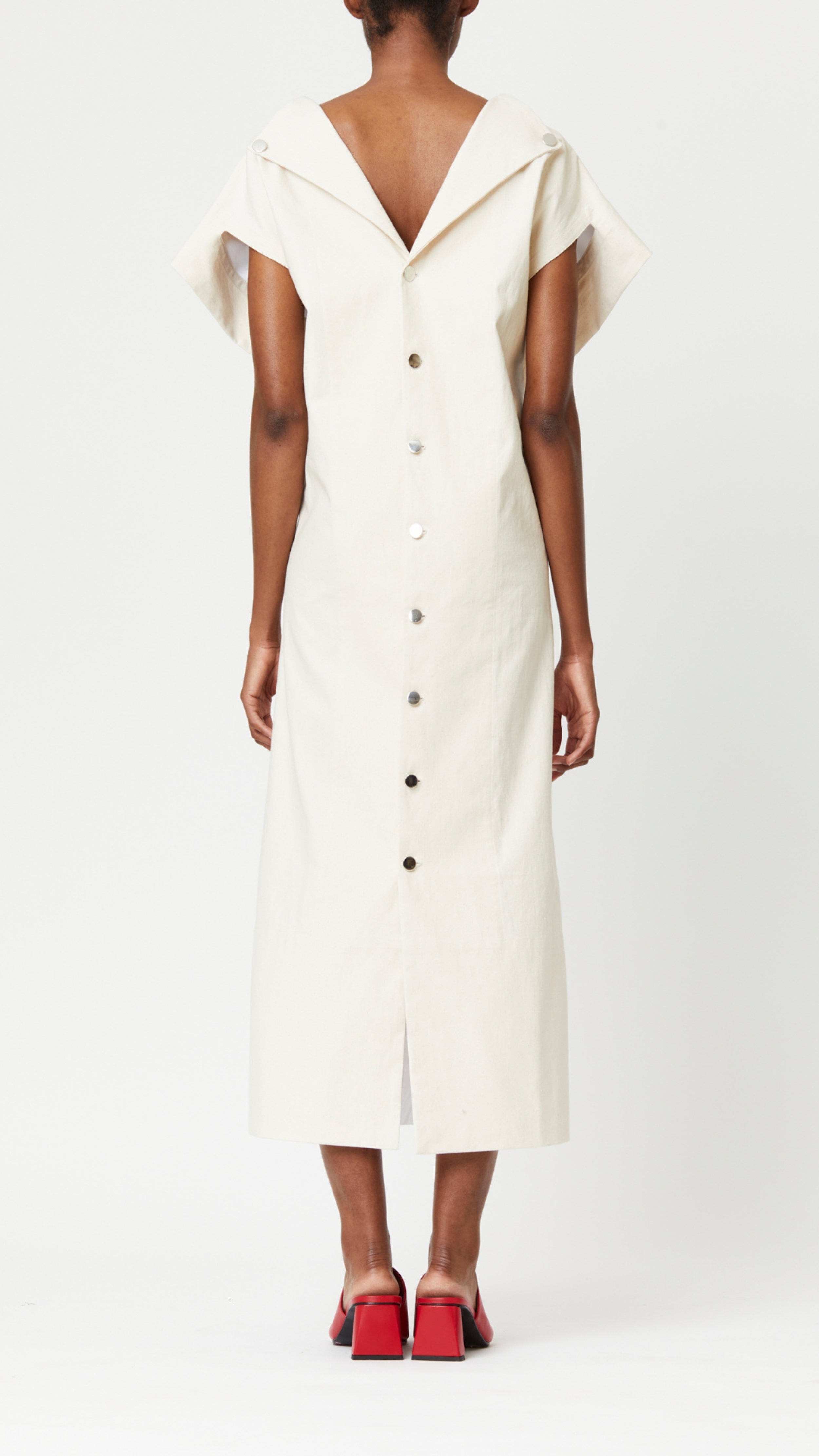 Plan C Smock Dress with Buttons in White & Calico. Summer dress. Smock dress with a front white panel over a soft calico interior. The front shoulder buttons create a dramatic sleeve and the dress has a v-neck in the back. A midi length dress and back button detailing. Shown on model facing back with button details.
