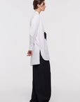 Plan C White Sartorial Poplin Shirt. Classic with a twist long white poplin blouse with front buttons. An added black ribbon detail in the front. Oversized cuffs at the long sleeves. Product photo shown from the sode.