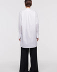 Plan C White Sartorial Poplin Shirt. Classic with a twist long white poplin blouse with front buttons. An added black ribbon detail in the front. Oversized cuffs at the long sleeves. Product photo shown from the back.