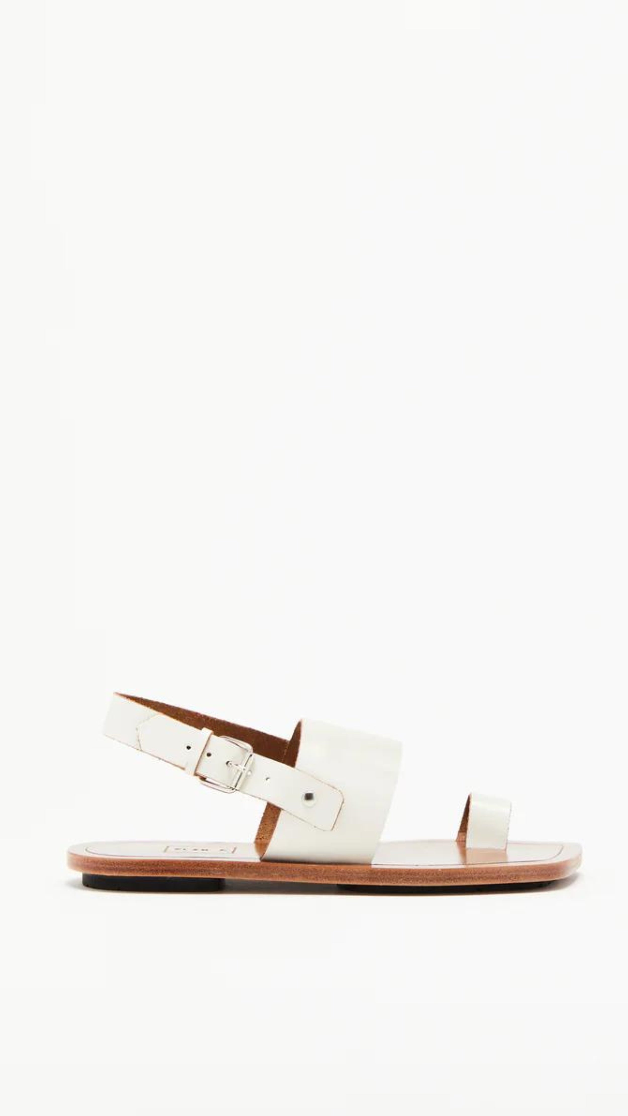 Plan C White Toe Ring Sandals. Made in Italy, these sandals have a strap across the foot, buckle around the heel and a ring of leather at the big toe. Flat sandals with a leather sole. Photo shown from the side.