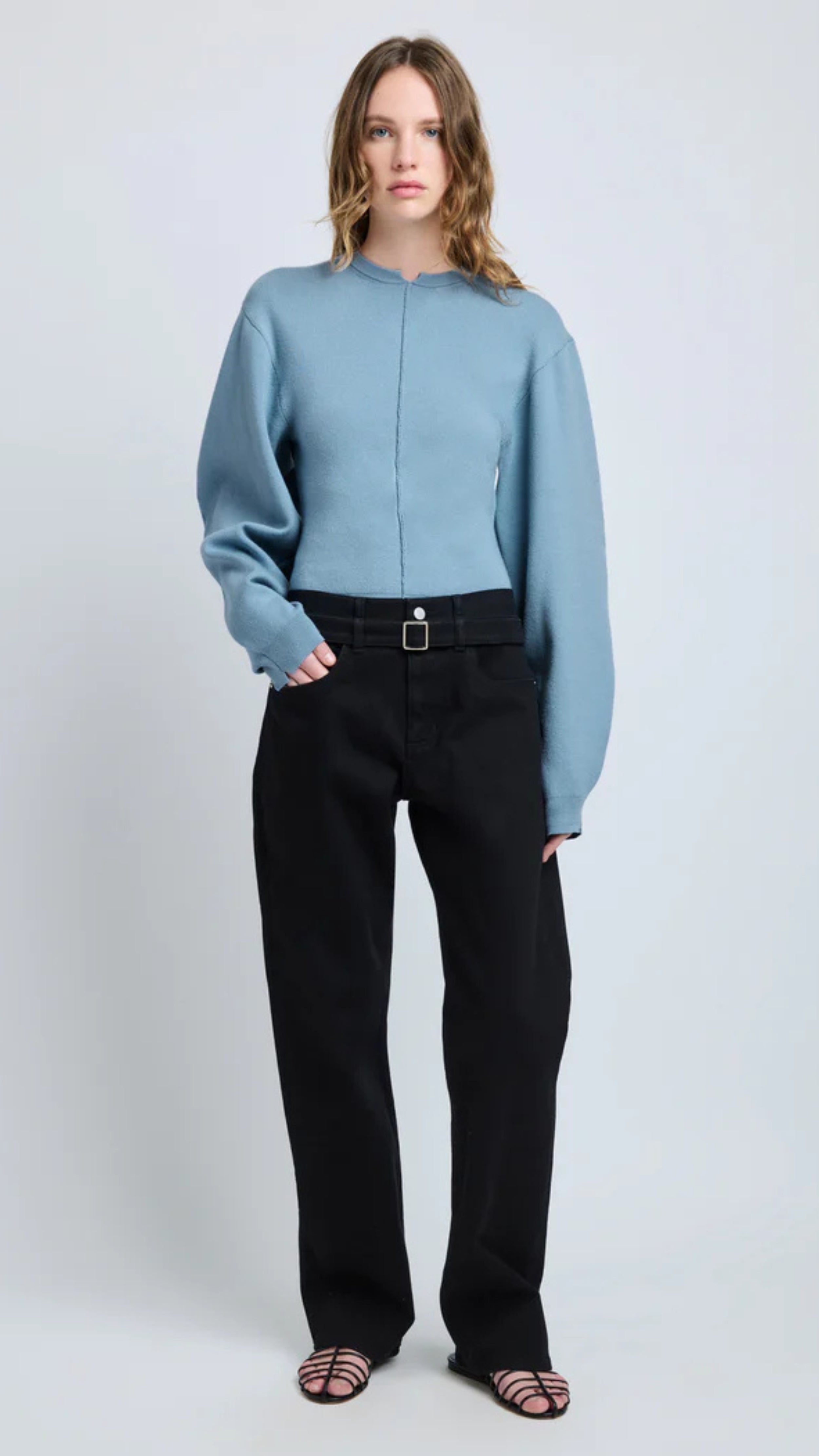 Woman wearing Carolina Sweater in lark blue Souffle Knit with classic crew neckline and puffed sleeves, paired with black pants.