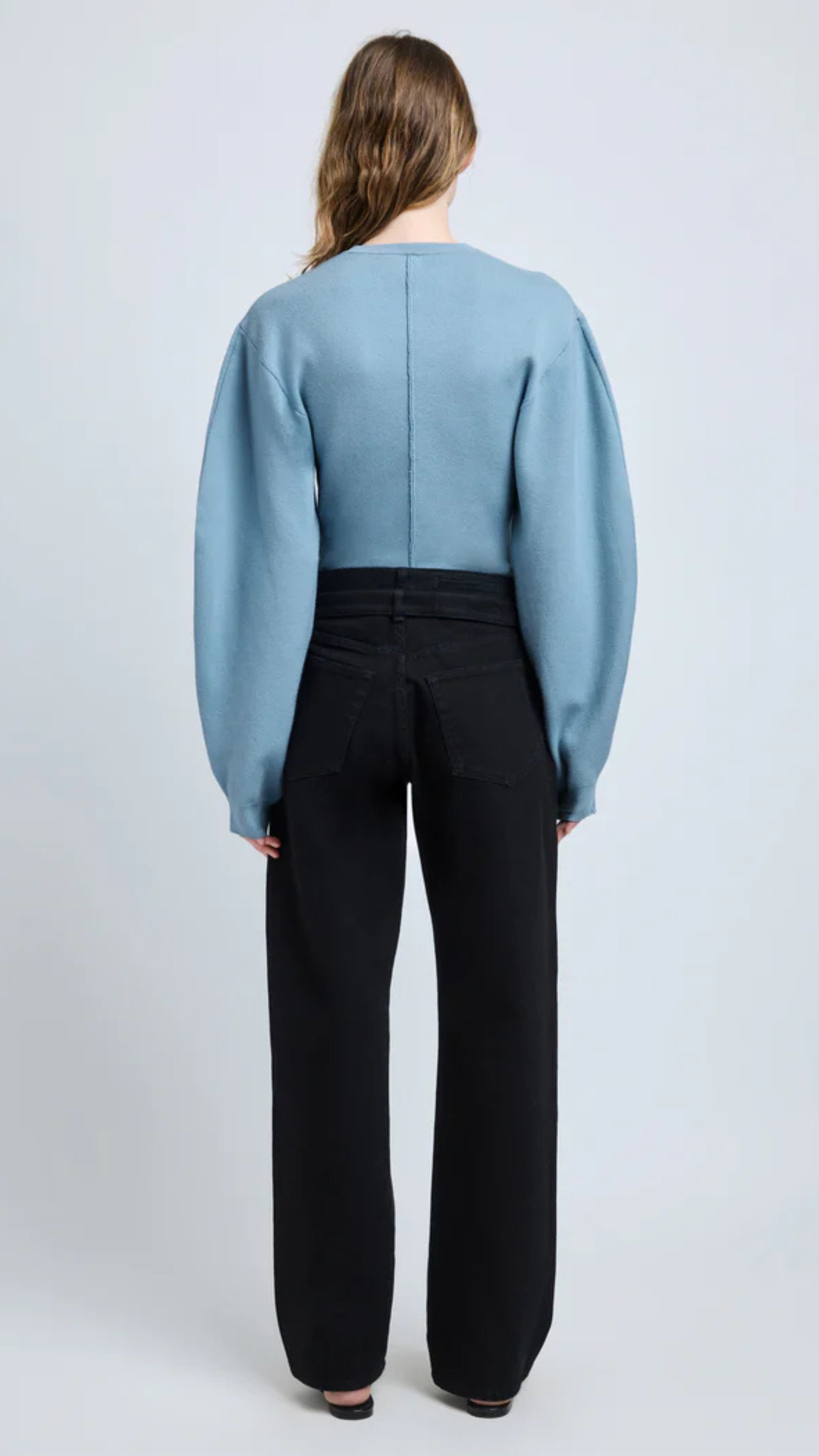 Woman wearing lark blue Souffle Knit Carolina Sweater with slightly puffed sleeves and classic crew neckline, seen from the back.