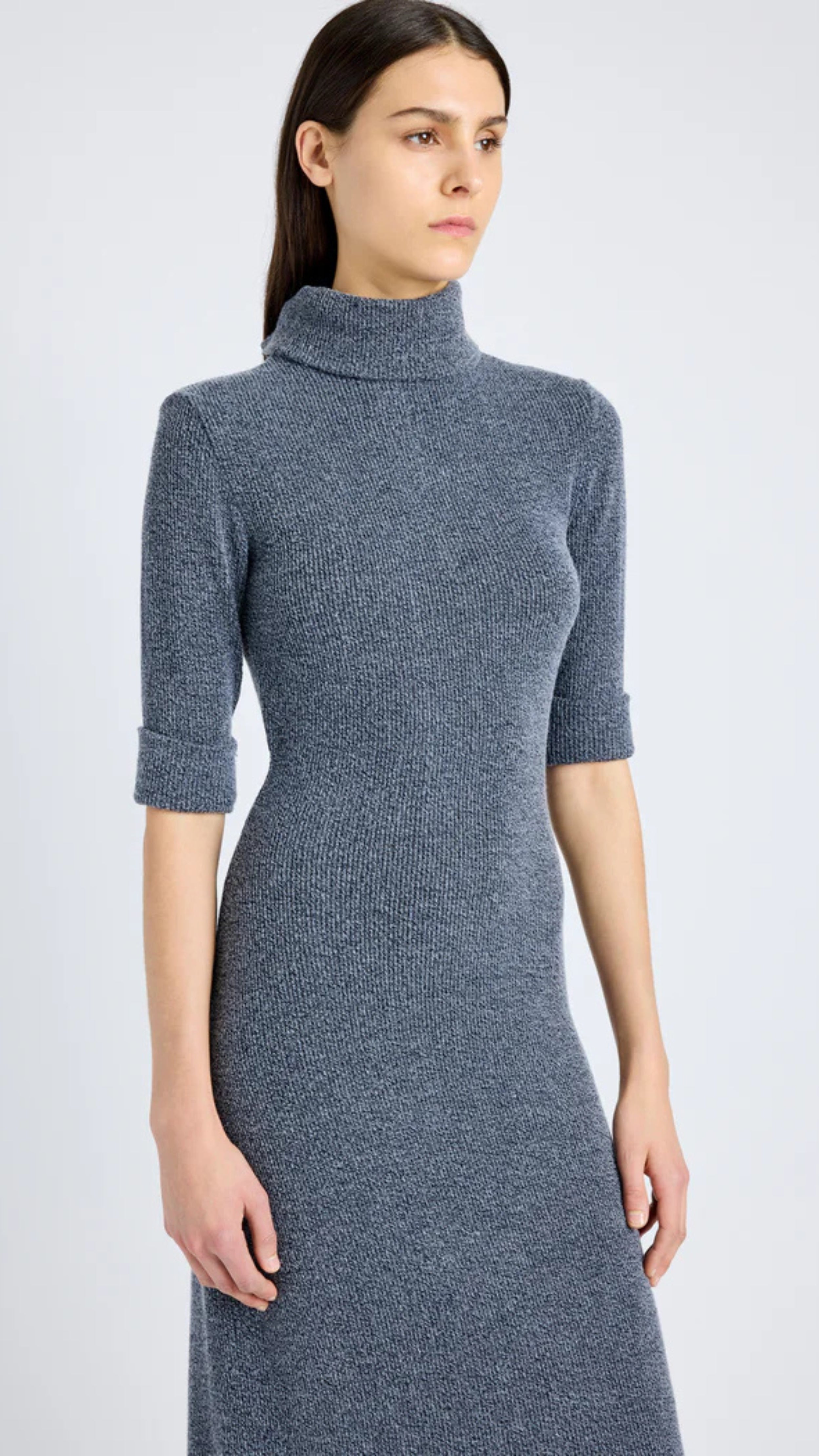 Grey blue boucle knit dress with slim silhouette, mock turtleneck, cap sleeves, buttoned back plaquette, and center slit hem.