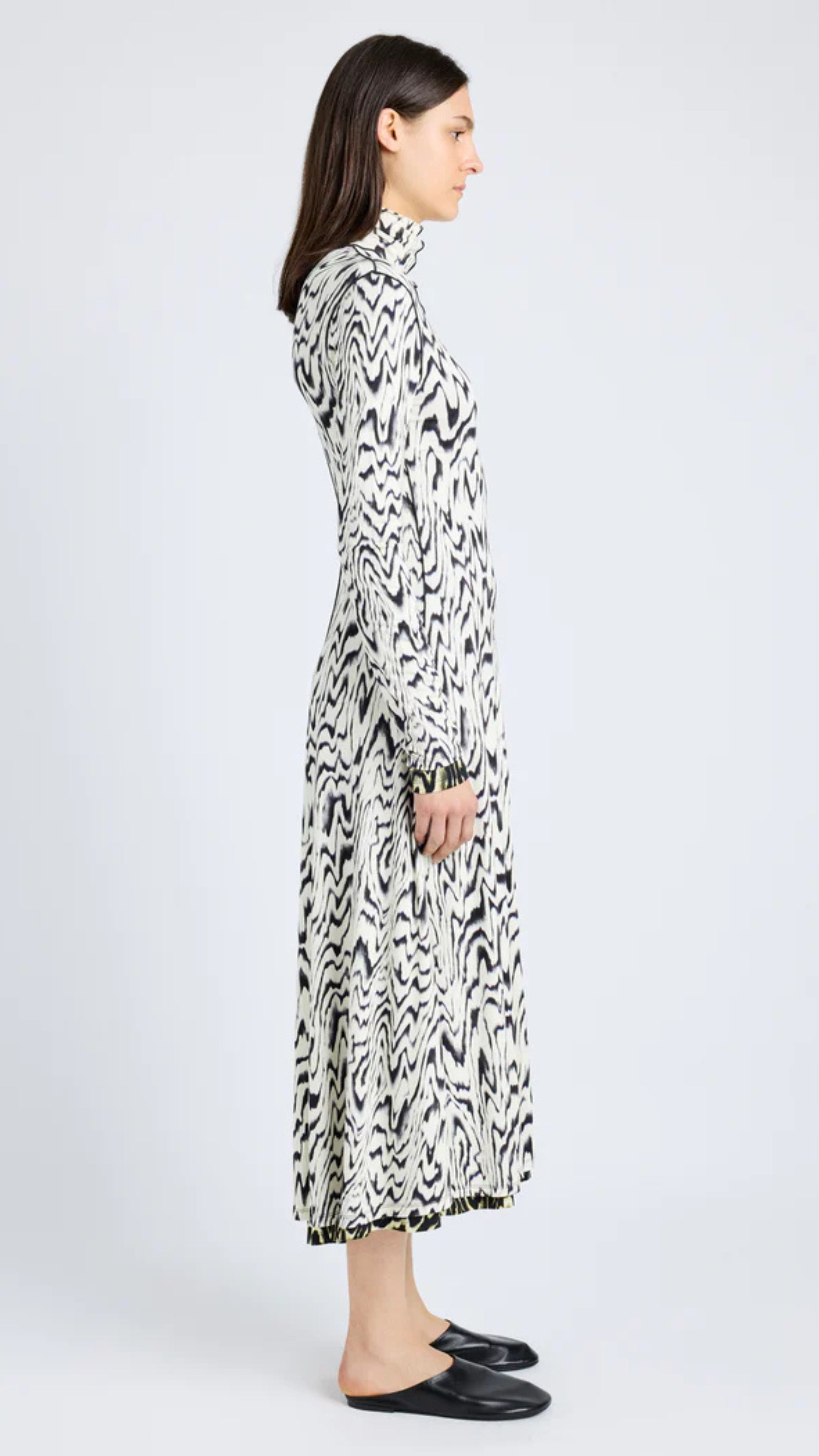 Marion Dress in black and white abstract printed jersey with foldable neck, long sleeves, and ankle-grazing hem, side view.