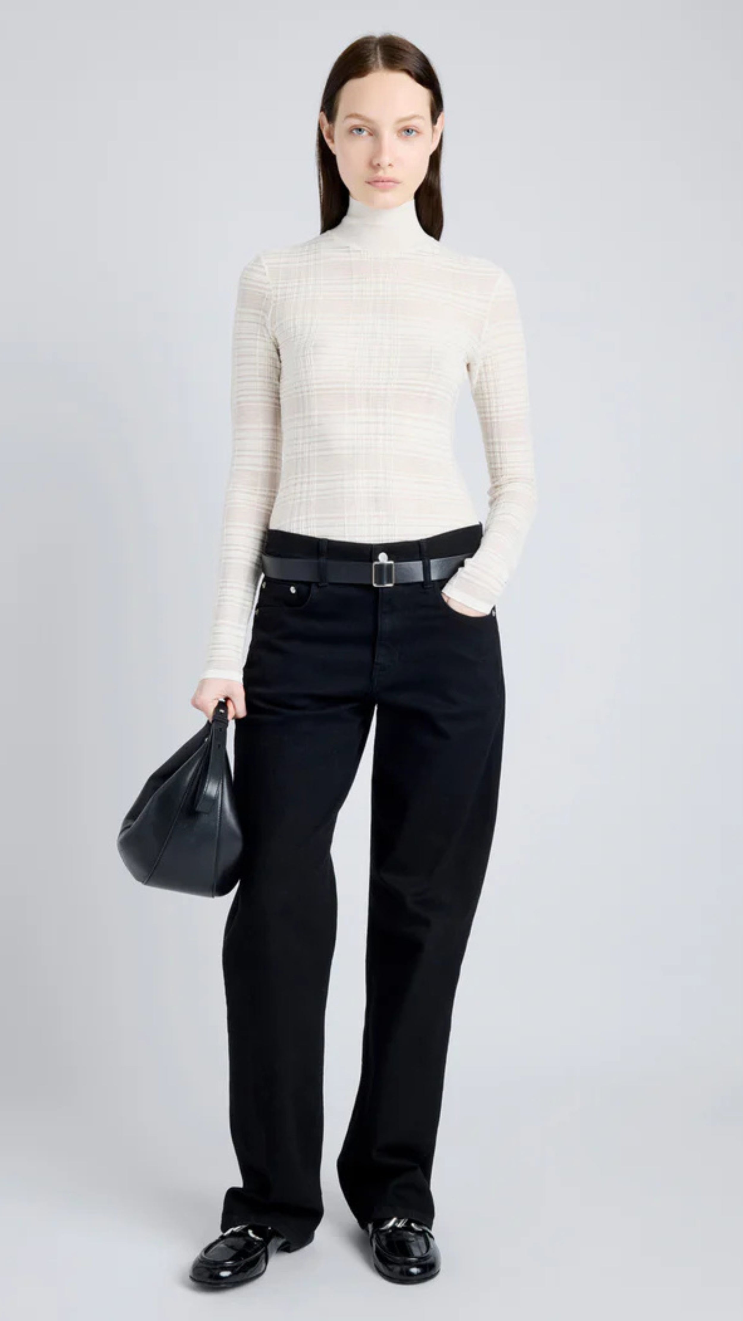 Woman wearing Stefanie Sweater in semi-sheer alabaster plaid knit with mock neckline and long sleeves, holding a black handbag.