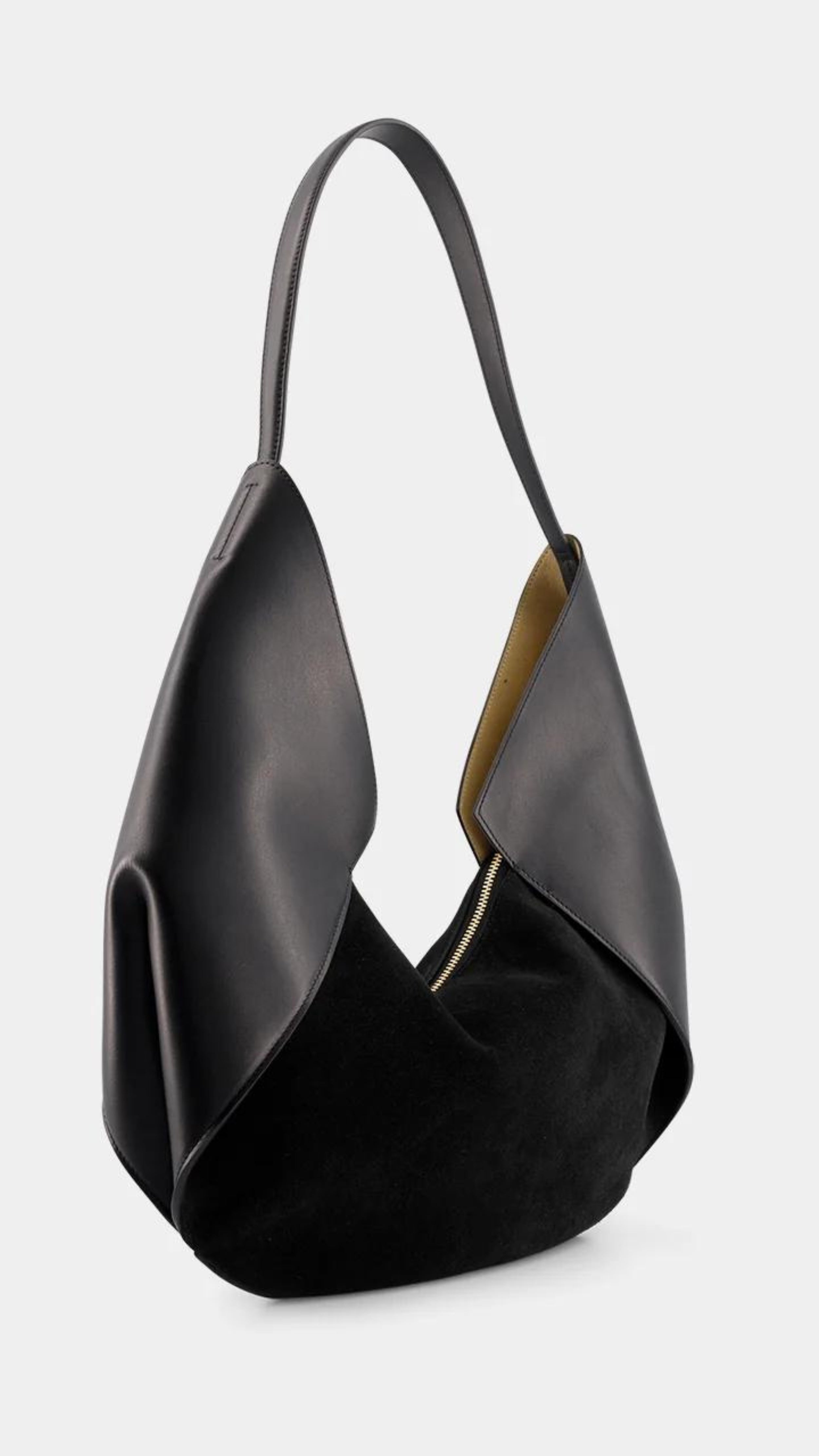 Ree Projects Riva Mini in Soft Calf and Suede in Black. Modern shaped soft black leather and suede purse. Small sized should bag with a zipper closure. Product photo from the front side view.