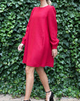 Rochas Paris Boucle Mini Dress in Red. Wool blend mini dress in a beautiful red. Lined in silk. The sleeves are cuffed and there are front pockets. This photo shows the model walking forward.