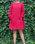 Rochas Paris Boucle Mini Dress in Red. Wool blend mini dress in a beautiful red. Lined in silk. The sleeves are cuffed and there are front pockets. This photo shows the model facing forward with her hands in the pockets.