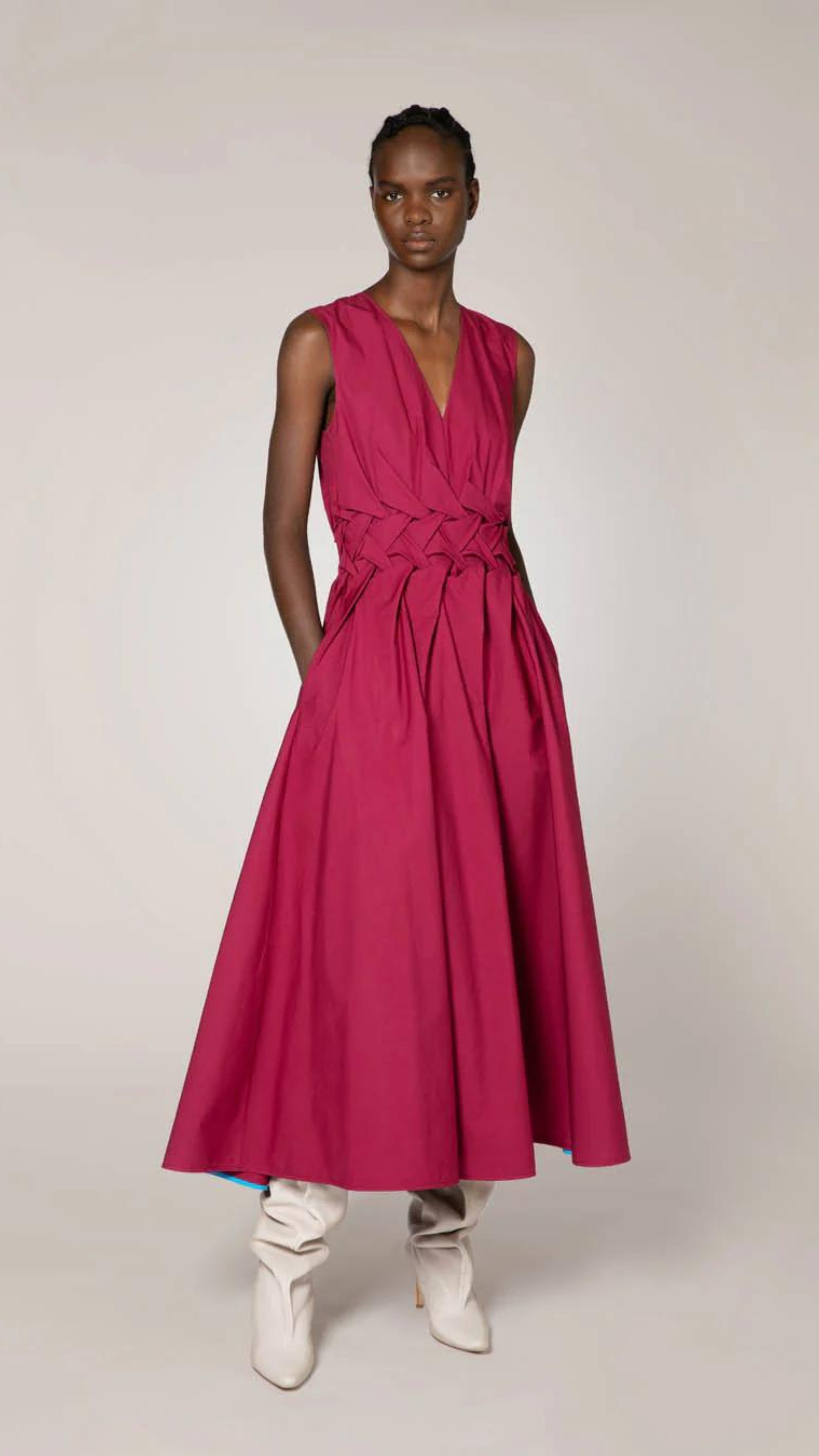 Roksanda Eifel Dress in Rose Wood colored cotton. With a V neckline, fitted waist with interested braided folding and a pleated skirt. Midi dress length. Photo shown on model facing front with hands in pockets.