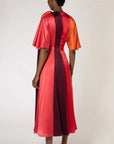 Roksanda Fiamma Dress. Silk midi dress in vertical panels of orange, rose red and burgundy. Features an architectural oval cut out at the top right front. Shown on model facing back.