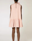 Roksanda Rosalina Dress. Soft pink with fun oversize twisted bow at neckline. Mini dress length with a dropped waist and pleated skirt panel. Shown on model facing the back.