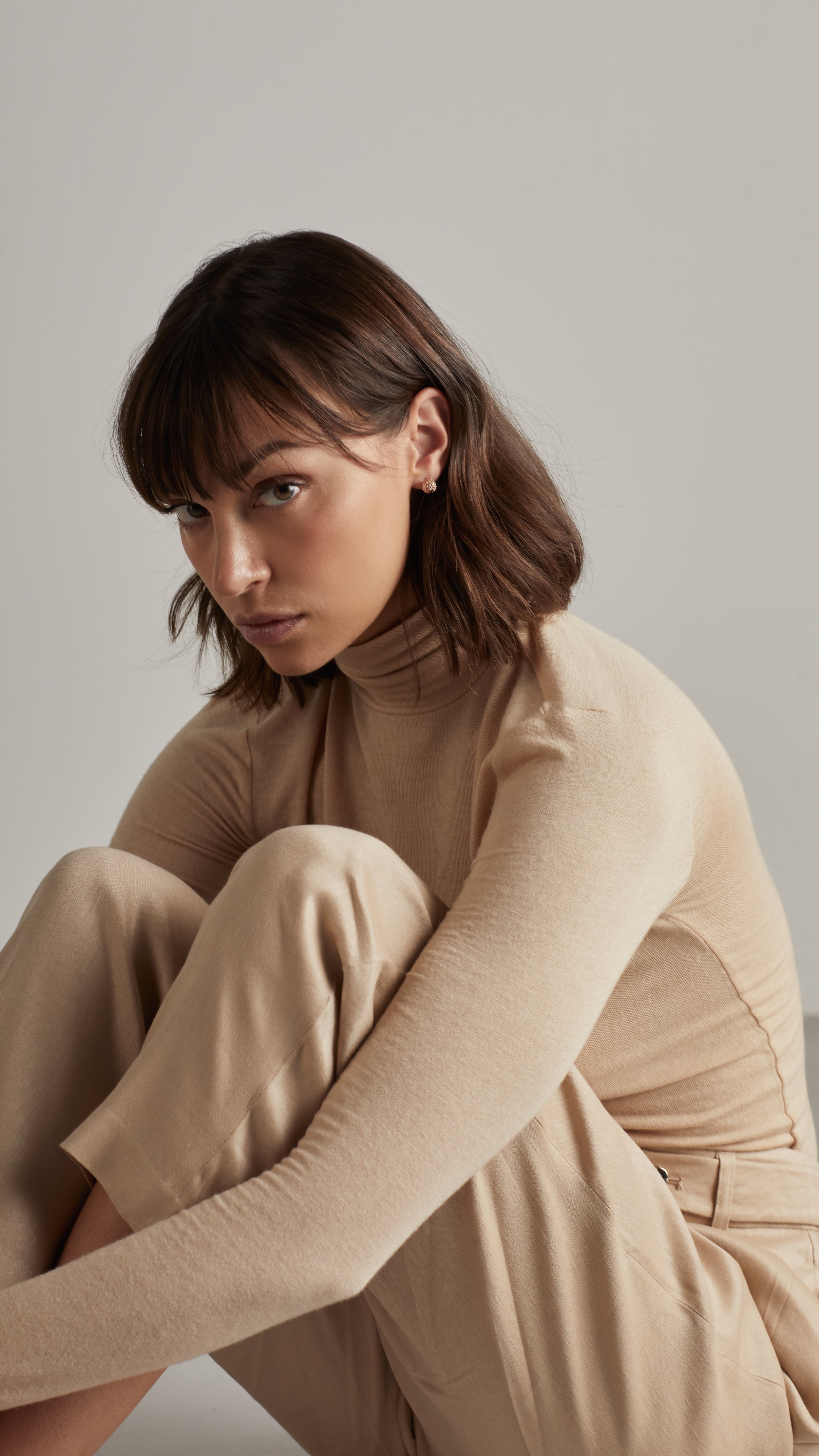 Woman wearing beige outfit and Iva Stud Earrings in a modern setting.