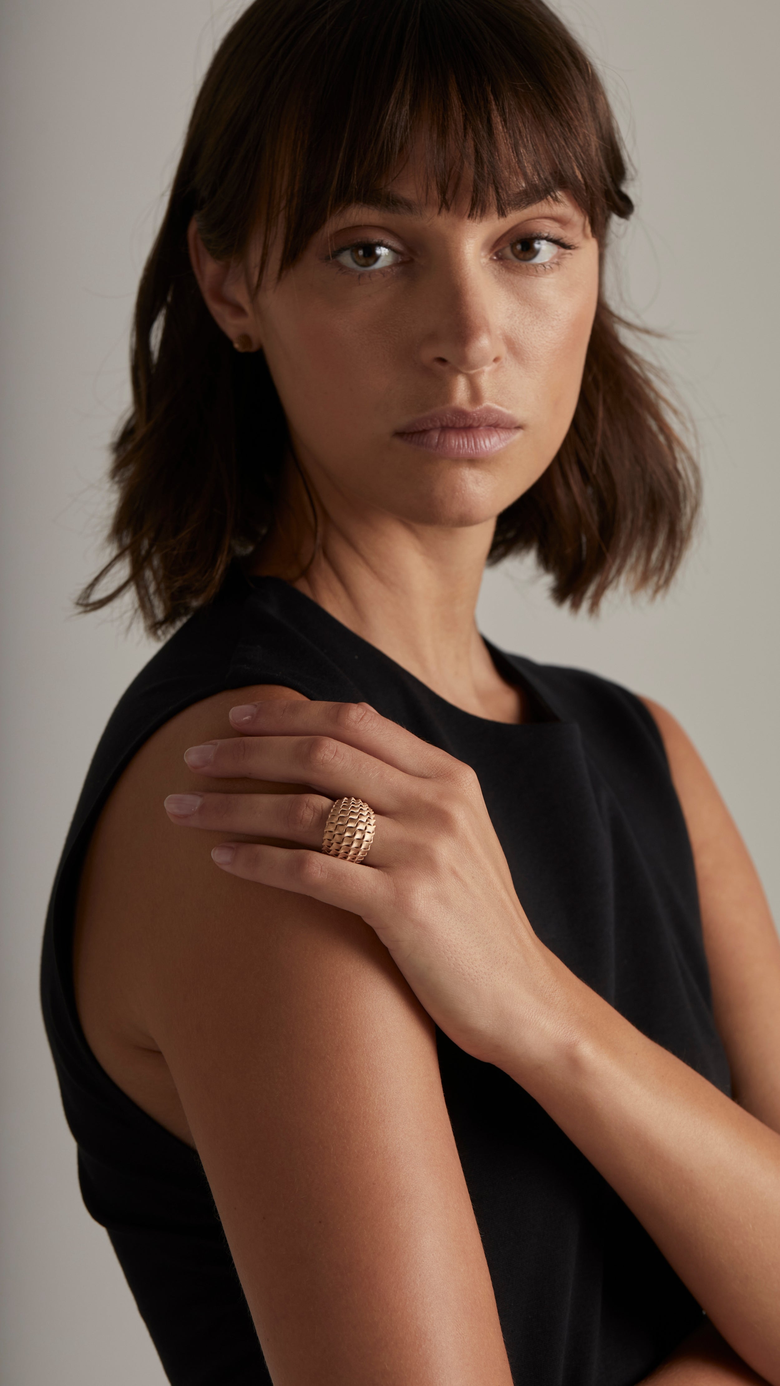 Woman wearing Emi Cocktail Ring in 18K Gold with architectural double curved grid design, part of fine jewelry collection.