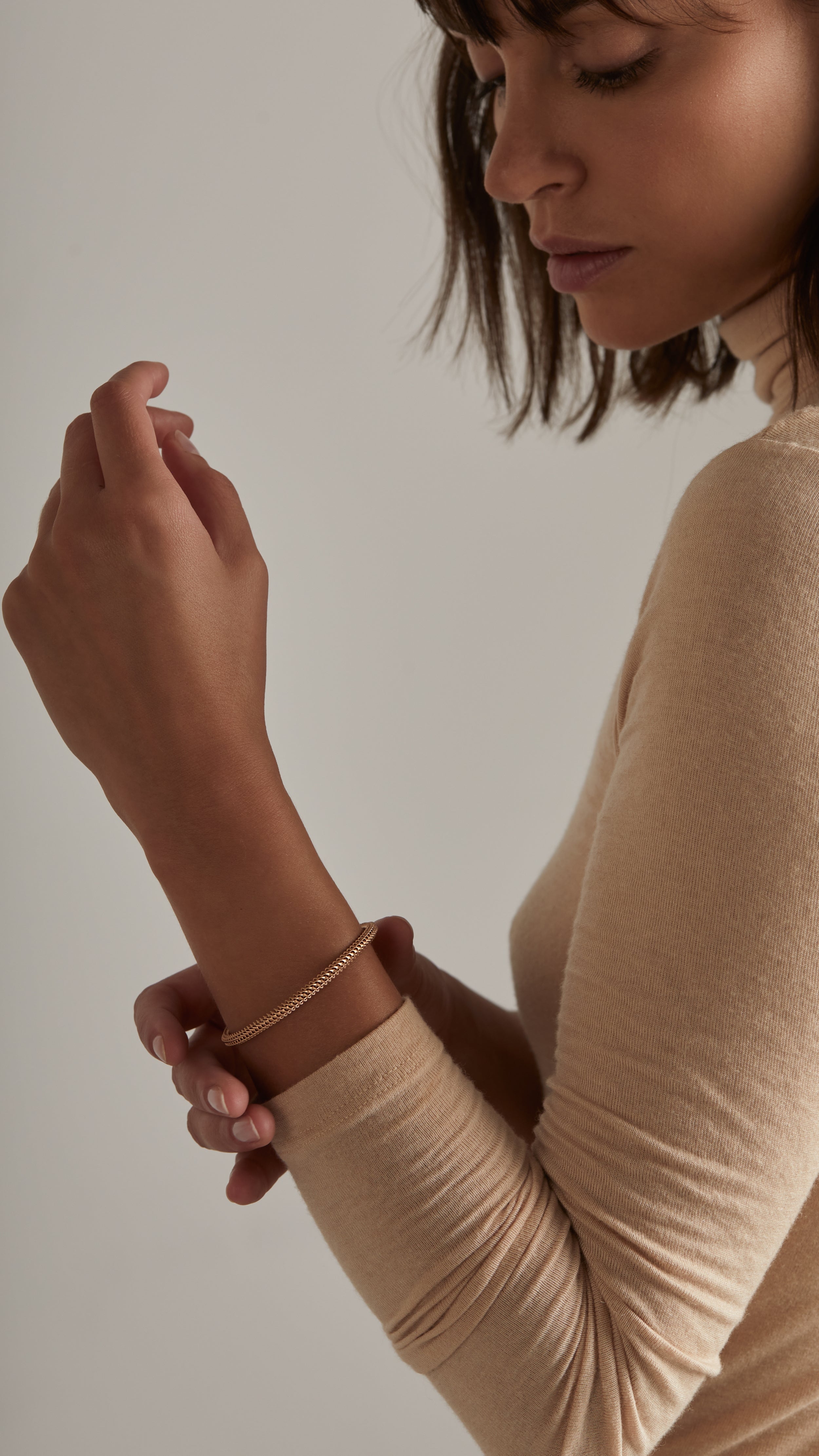 Woman wearing Ina Bangle in 18K gold with interwoven grid-like shells, showcasing Sian Jewels' modern architectural jewelry design.