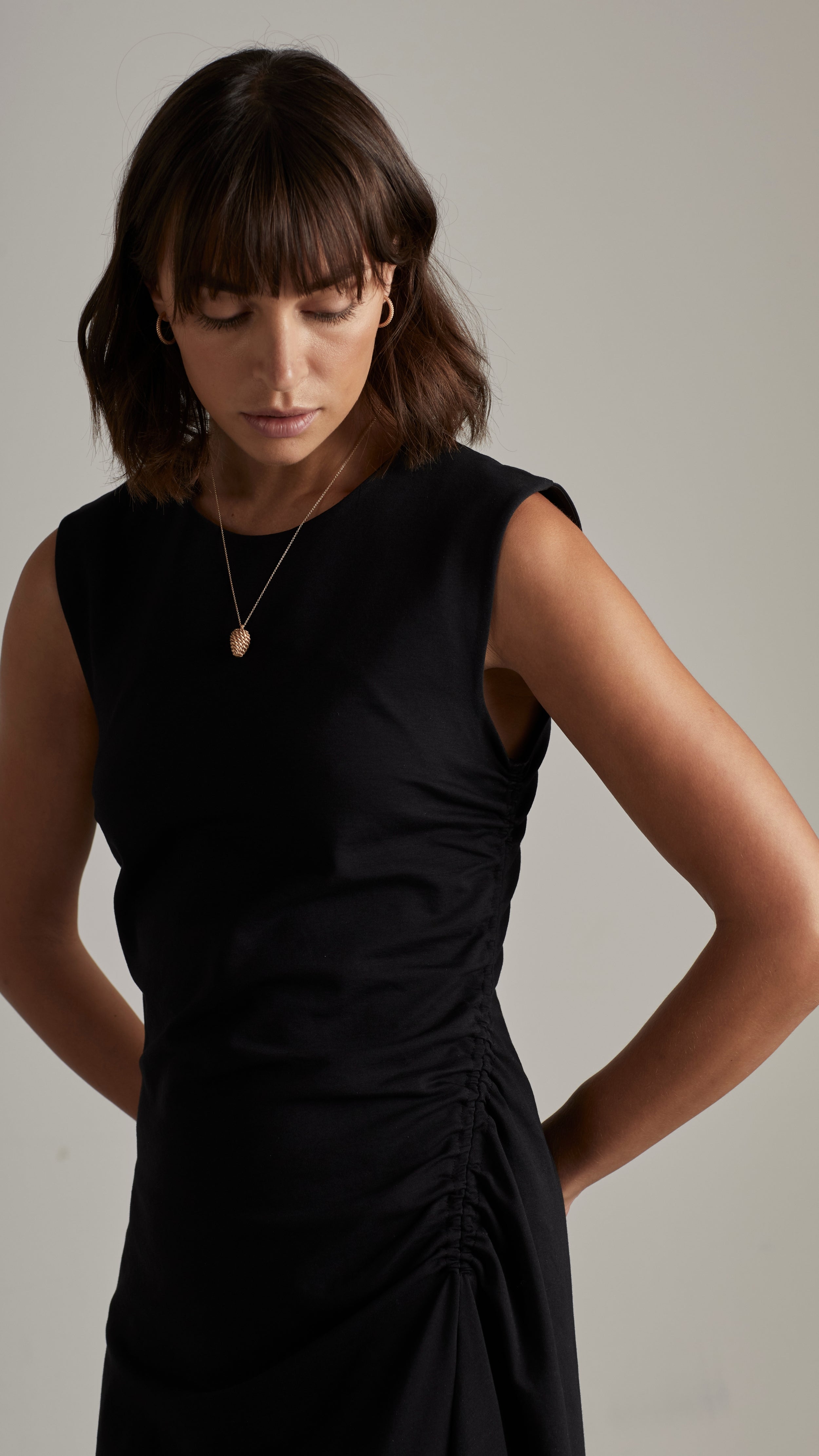 Woman wearing a black dress and a small pendant necklace.