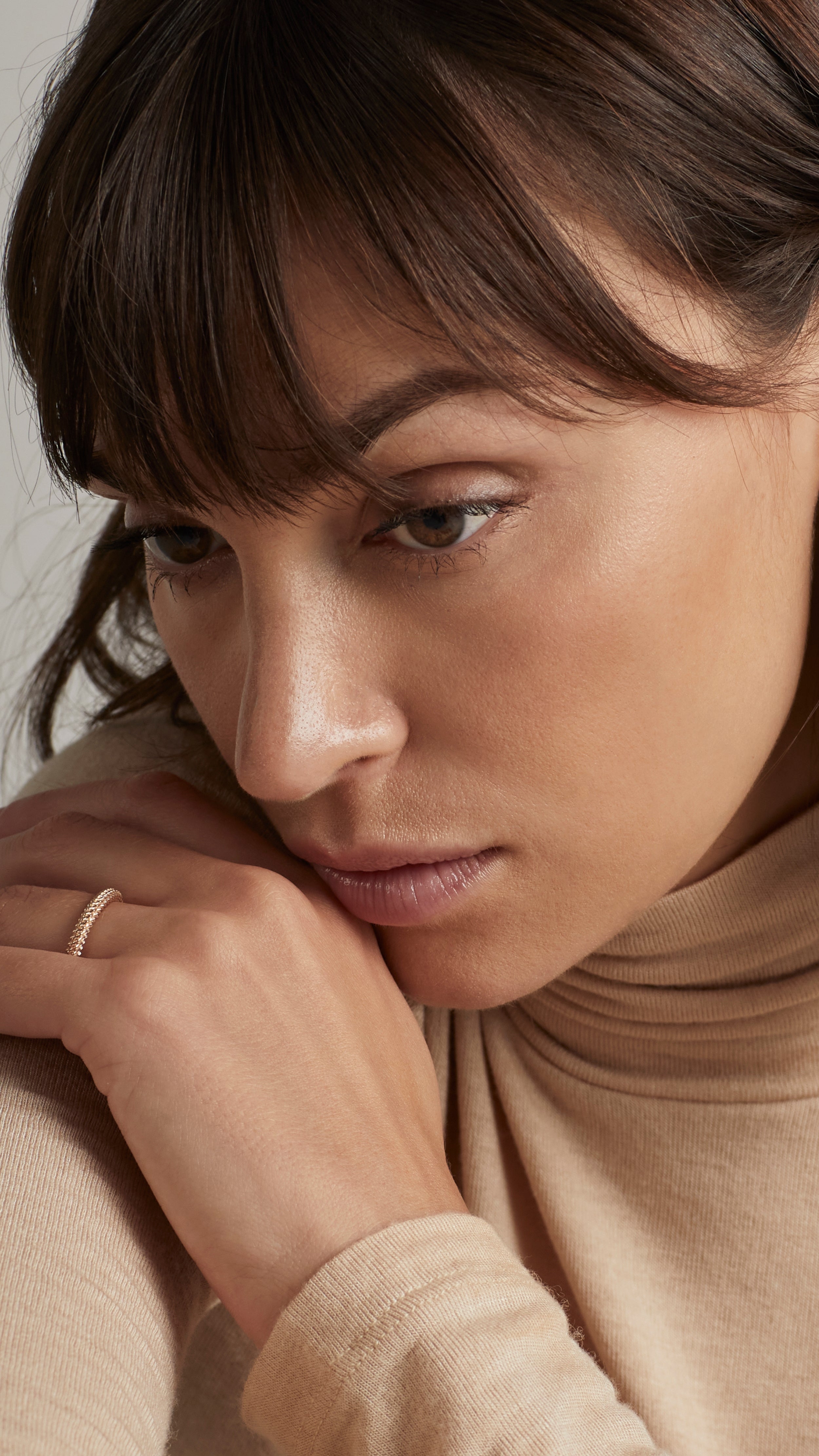 Woman wearing Nio Ring with interwoven strands, showcasing 18K gold fine jewelry.