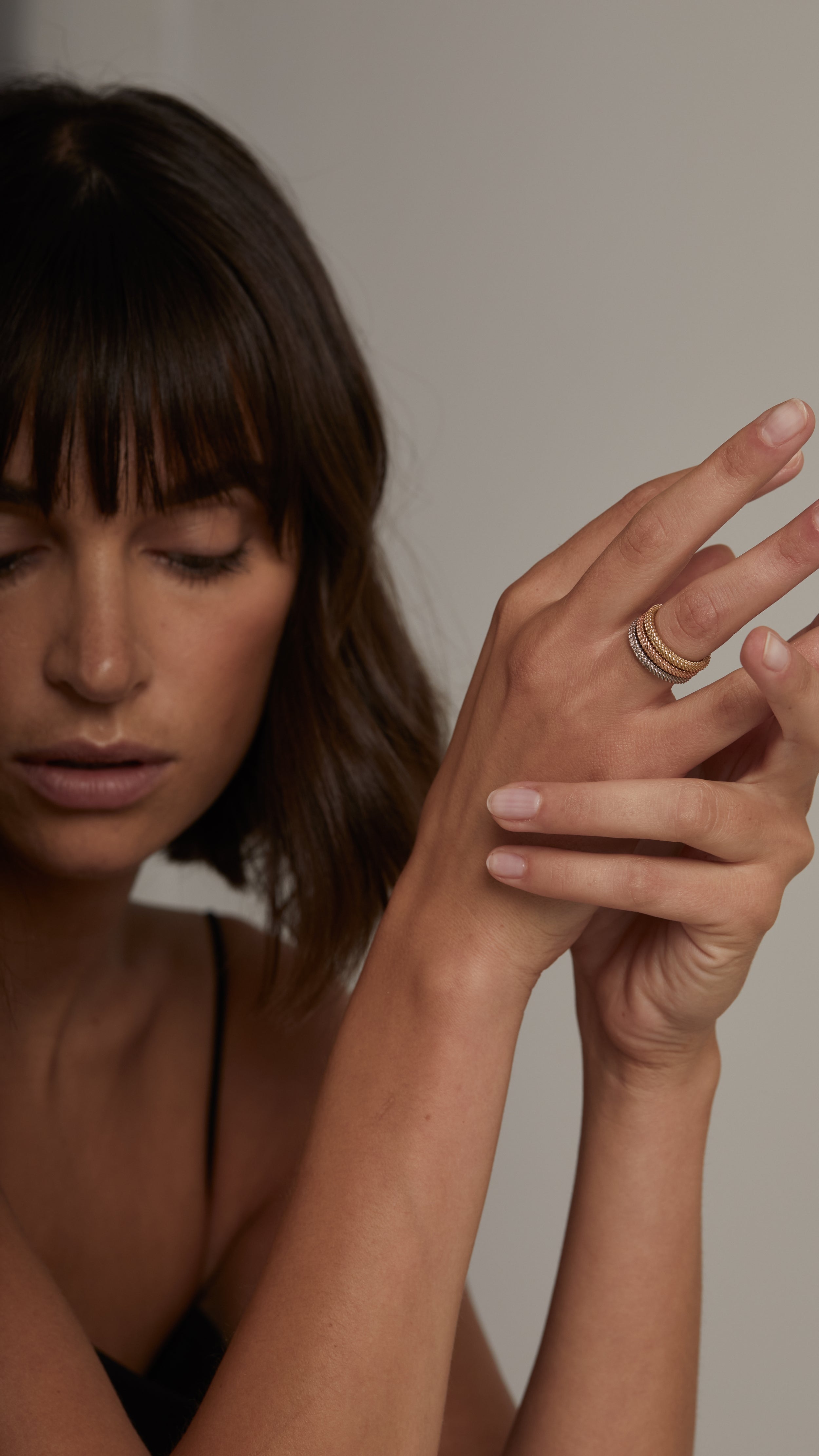 Woman wearing Nio Ring in 18K gold, showcasing two interwoven strands and elegant modern design.