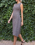 St. John Knits Asymmetrical Boucle Dress in navy, ecru and burgundy. This sleeveless dress has elegant one sided pleating and is midi length. Shown on the model facing front and to the side.