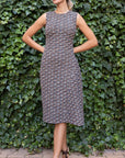 St. John Knits Asymmetrical Boucle Dress in navy, ecru and burgundy. This sleeveless dress has elegant one sided pleating and is midi length. Shown on the model facing front.
