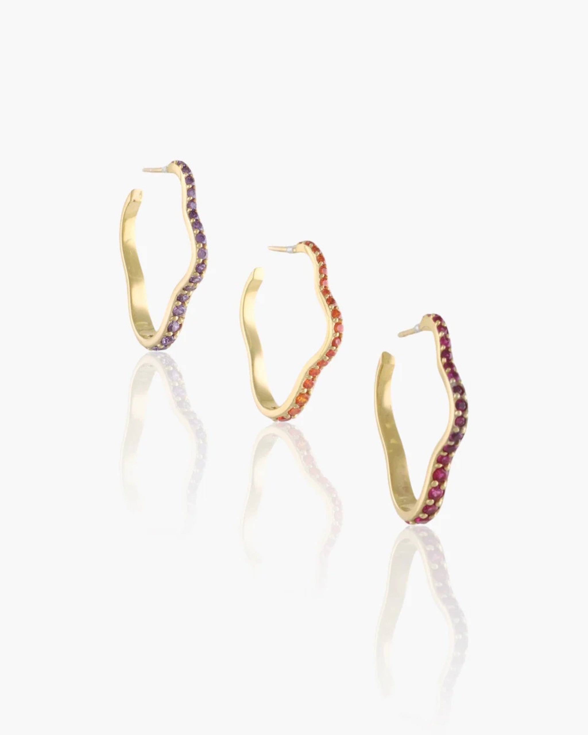 18k gold wavy hoop earring with colored sapphires by K Salamoon, photographed on white background.