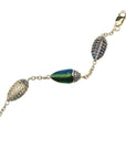 Bibi van der Velden Scarab Multi Color Bracelet. Five scarabs charms connected with 18k yellow gold and sterling silver chains form this charm bracelet.  Each scarabs featured here are set with real scarab wings, brown diamonds, blue sapphires, and tsavorites. Close up of pave scarabs.