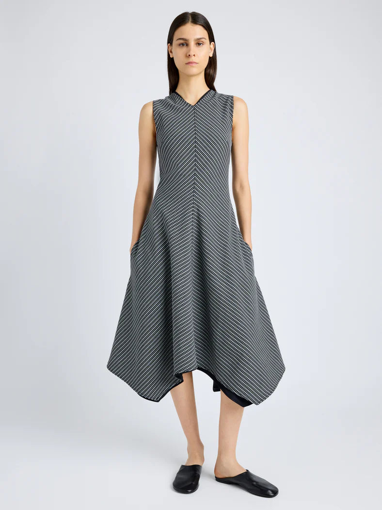 Woman wearing black and white check Proenza Schouler Layla Dress with V-neck, slim bodice, A-line silhouette, and asymmetrical hem.