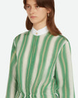 Wales Bonner Balance Dress Made in Italy in a lightweight silk blend. The midi dress has long sleeves, a white collared neck, and green and white stripes. The shirt dress has an adjustable drawstring waist, buttons up the front, and deep front pockets. Shown on model with detail of front top.