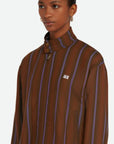 Wales Bonner Life Jacket Italian-made jacket crafted from lightweight herringbone wool in deep brown and blue stripe colors. This coat features long sleeves and a front zipper. Shown on model facing front and close up.
