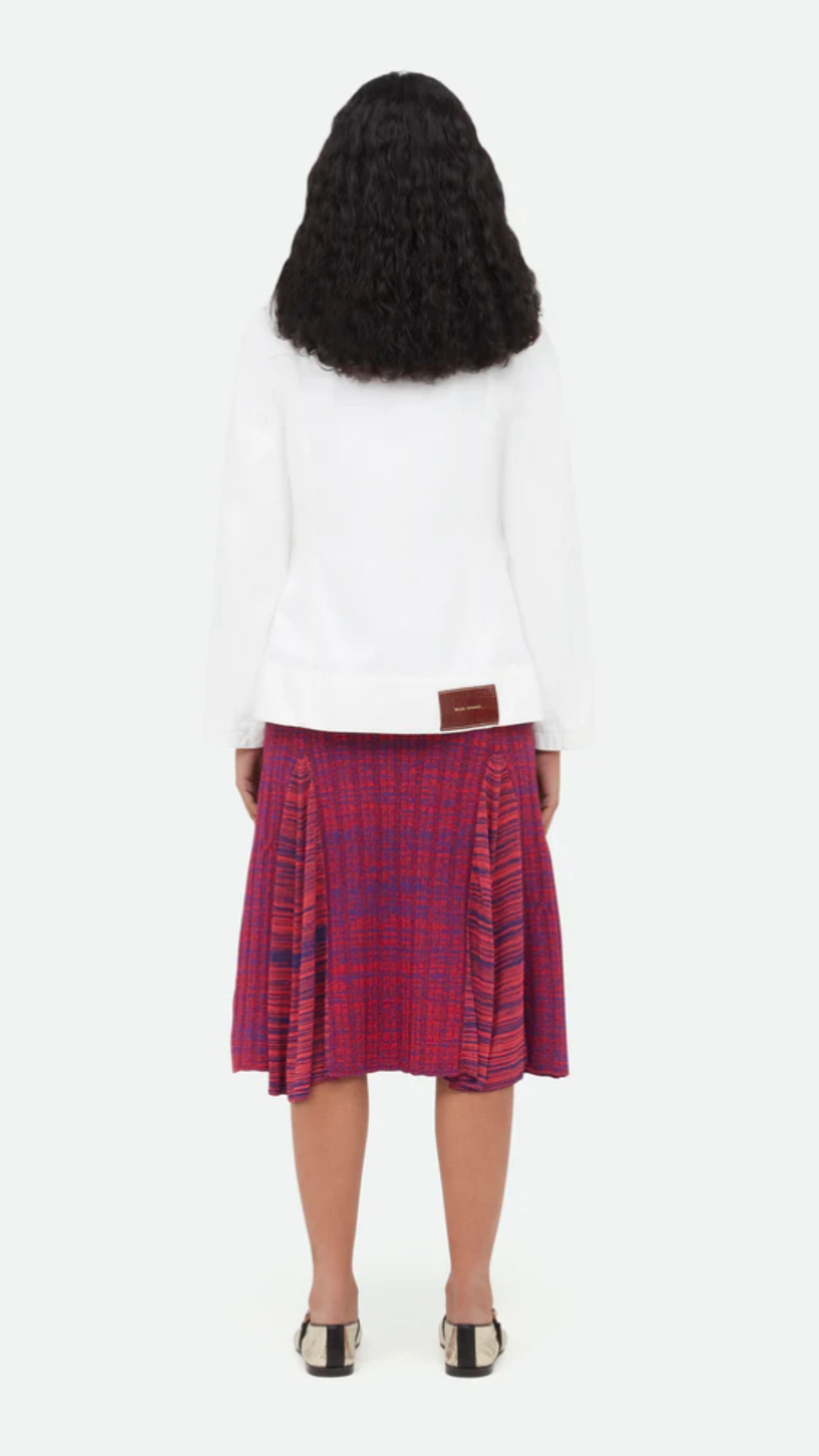 Wales Bonner Nile Skirt This A-line midi skirt features an elastic waist and beautiful pleats at the mid-thigh. Woven striped pattern in red and purples. The skirt falls to knee length. Shown on model facing back
