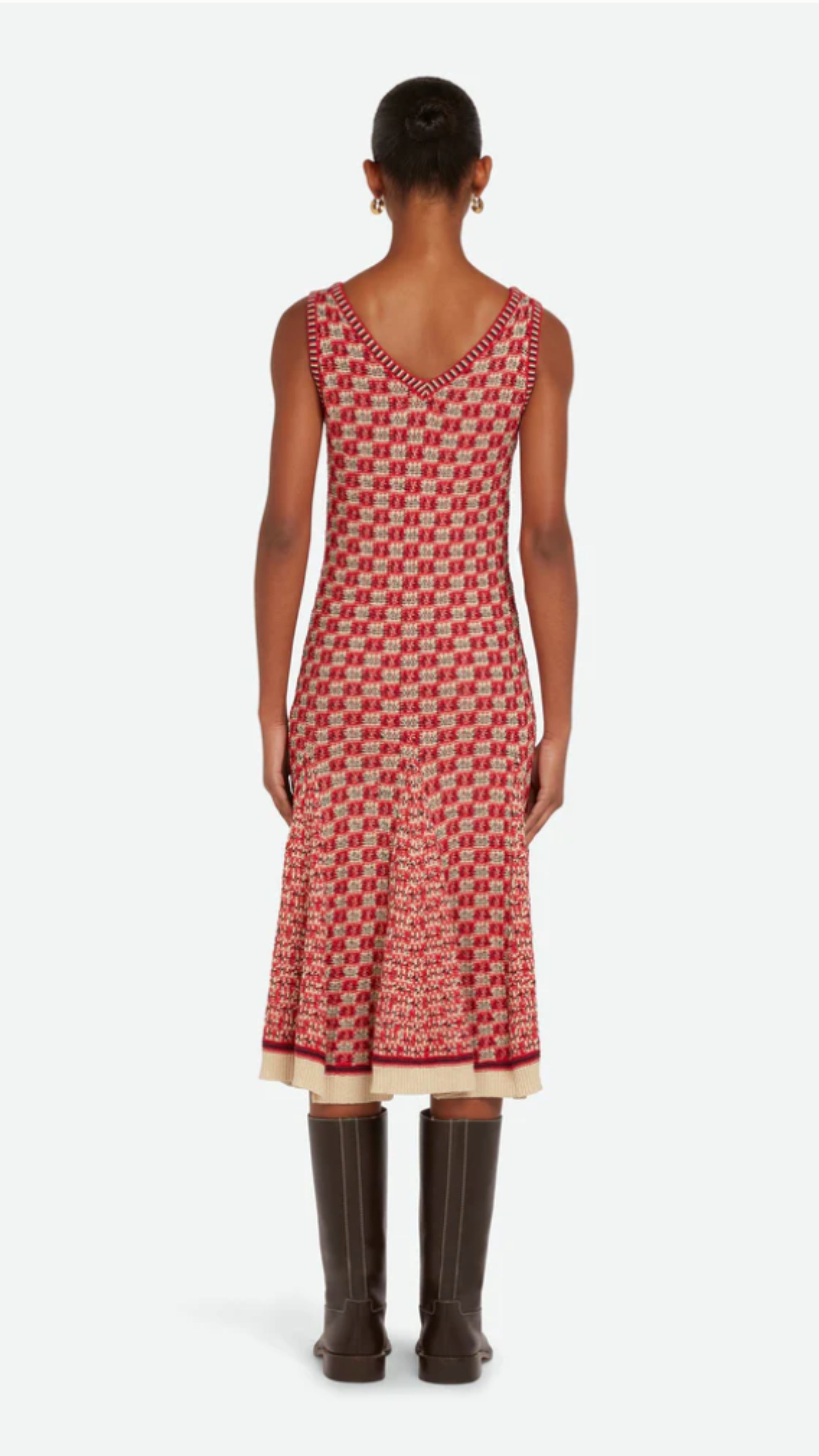 Wales Bonner Soar Godet Dress Woven in an light weight summer Italian cotton knit. This midi length dress has a checkered pattern in red, ivory and black. It has a v-neckline and slightly flared skirt that falls just below the knee. Shown on model facing back.