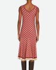 Wales Bonner Soar Godet Dress Woven in an light weight summer Italian cotton knit. This midi length dress has a checkered pattern in red, ivory and black. It has a v-neckline and slightly flared skirt that falls just below the knee. Shown on model facing back.