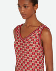 Wales Bonner Soar Godet Dress Woven in an light weight summer Italian cotton knit. This midi length dress has a checkered pattern in red, ivory and black. It has a v-neckline and slightly flared skirt that falls just below the knee. Shown on model facing front side.
