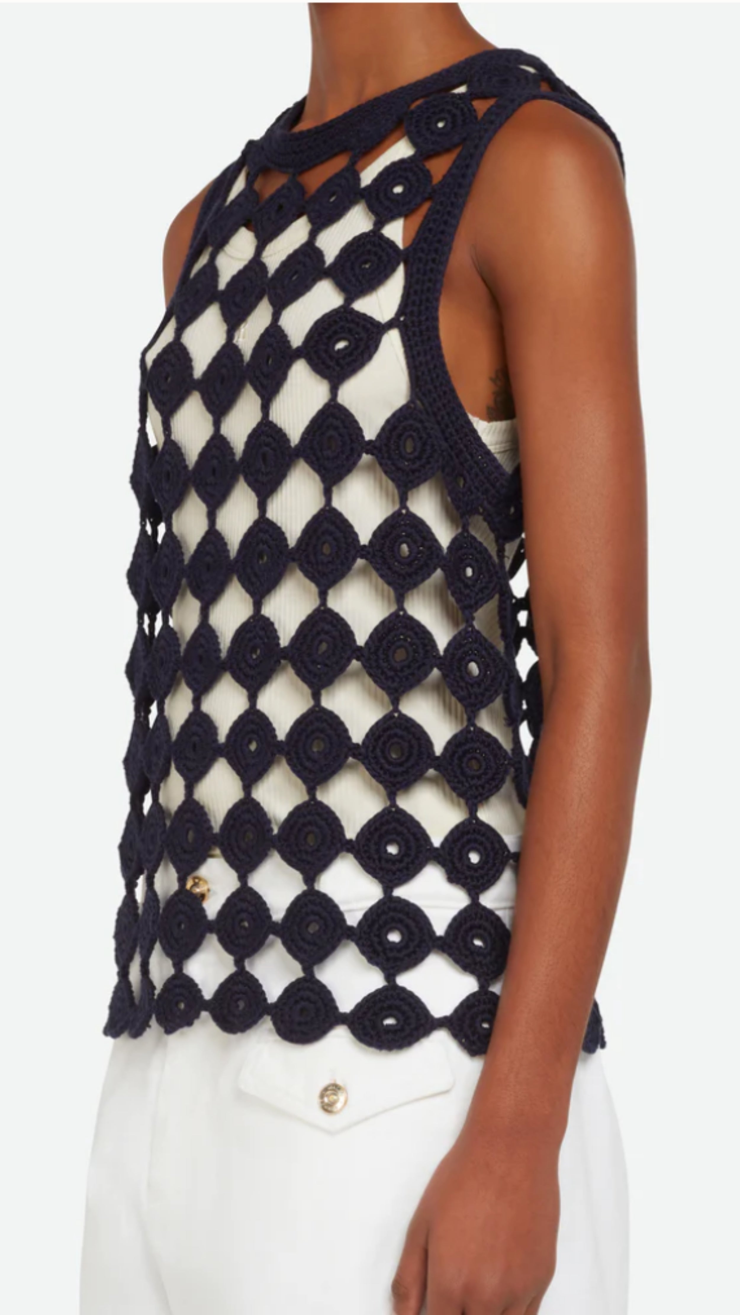 Wales Bonner Stanza Knit Vest Crafted from an open knit cotton and lycra blend in navy blue. A sleeveless style vest top with a rounded neckline. Shown on a model facing side.