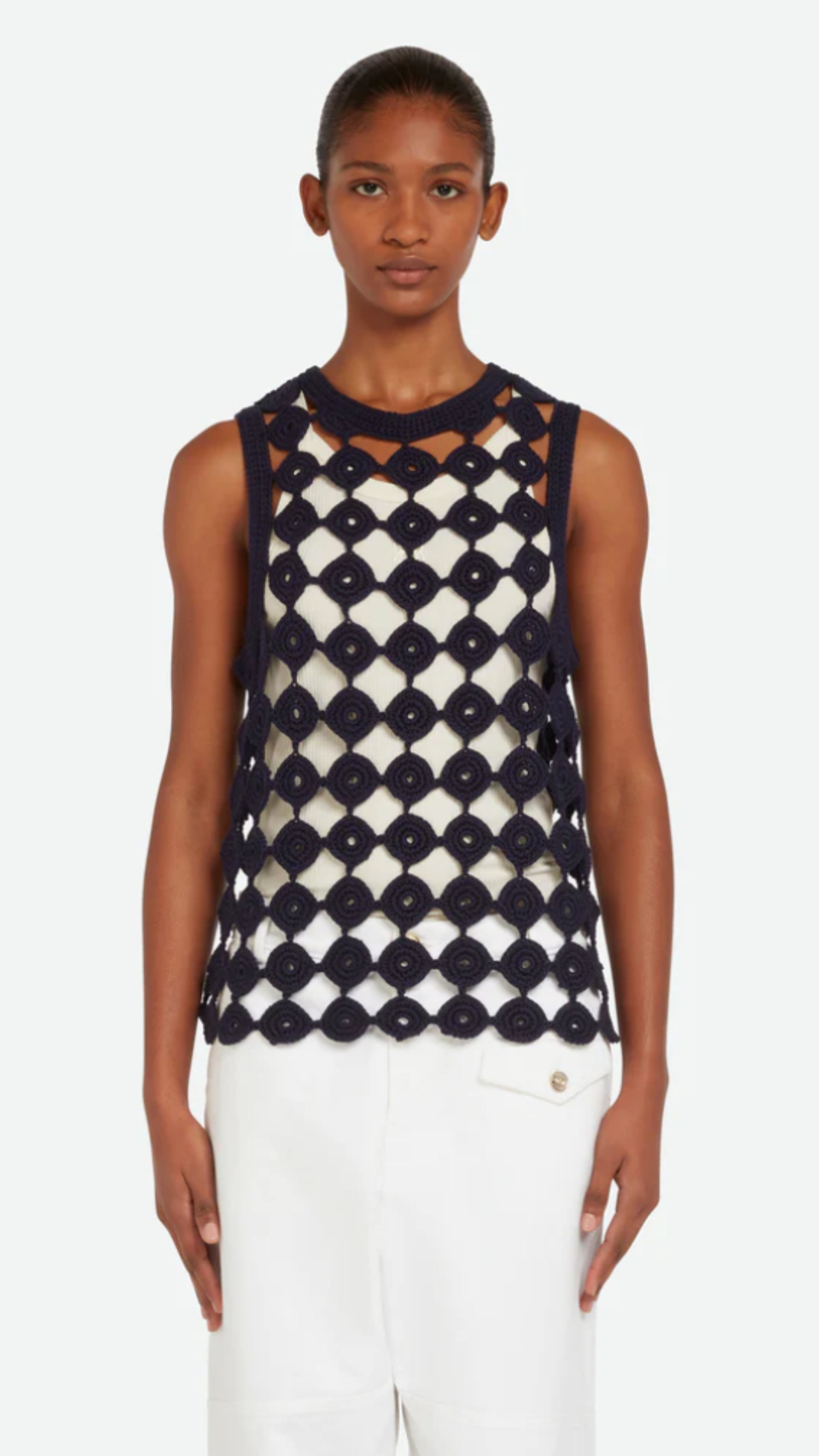 Wales Bonner Stanza Knit Vest Crafted from an open knit cotton and lycra blend in navy blue. A sleeveless style vest top with a rounded neckline. Shown on a model facing front.