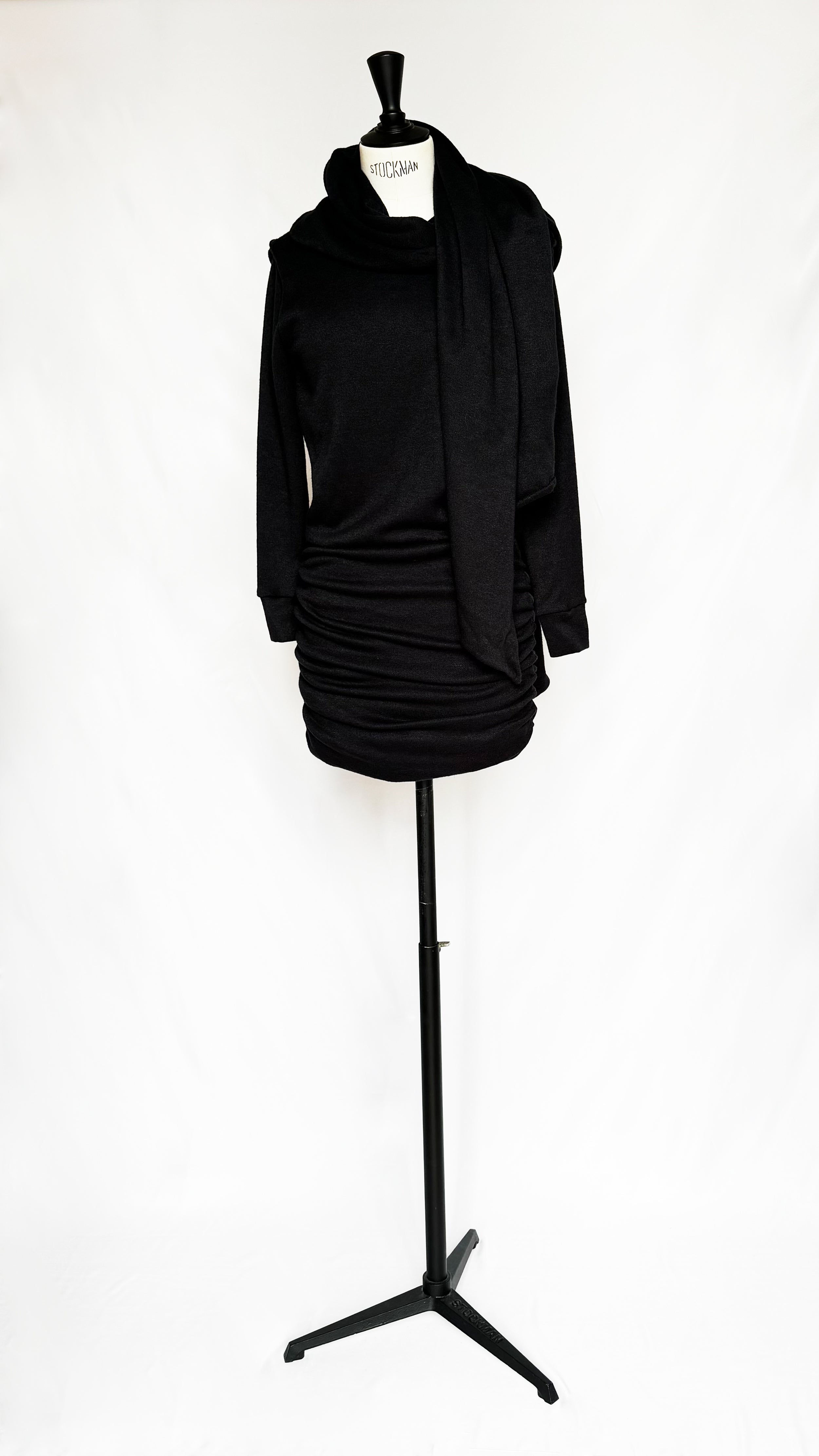 Black knit Gstaad Mini Dress with long sleeves, wrap-around scarf, open back, and ruched skirt by Leslie Amon on mannequin.