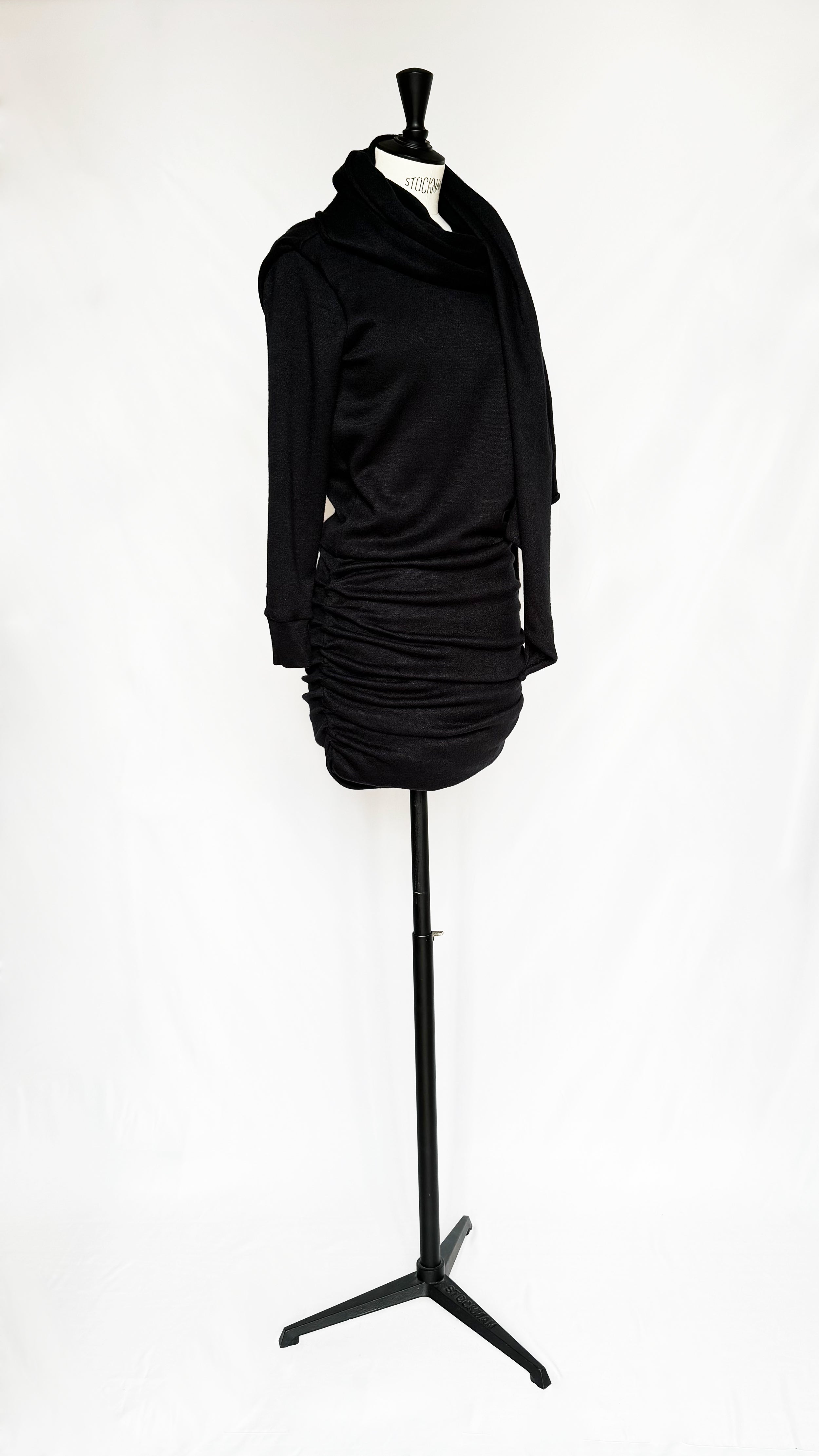 Black Gstaad Mini Dress by Leslie Amon featuring soft knit, long sleeves, wrap-around scarf, ruched skirt, and open back design.