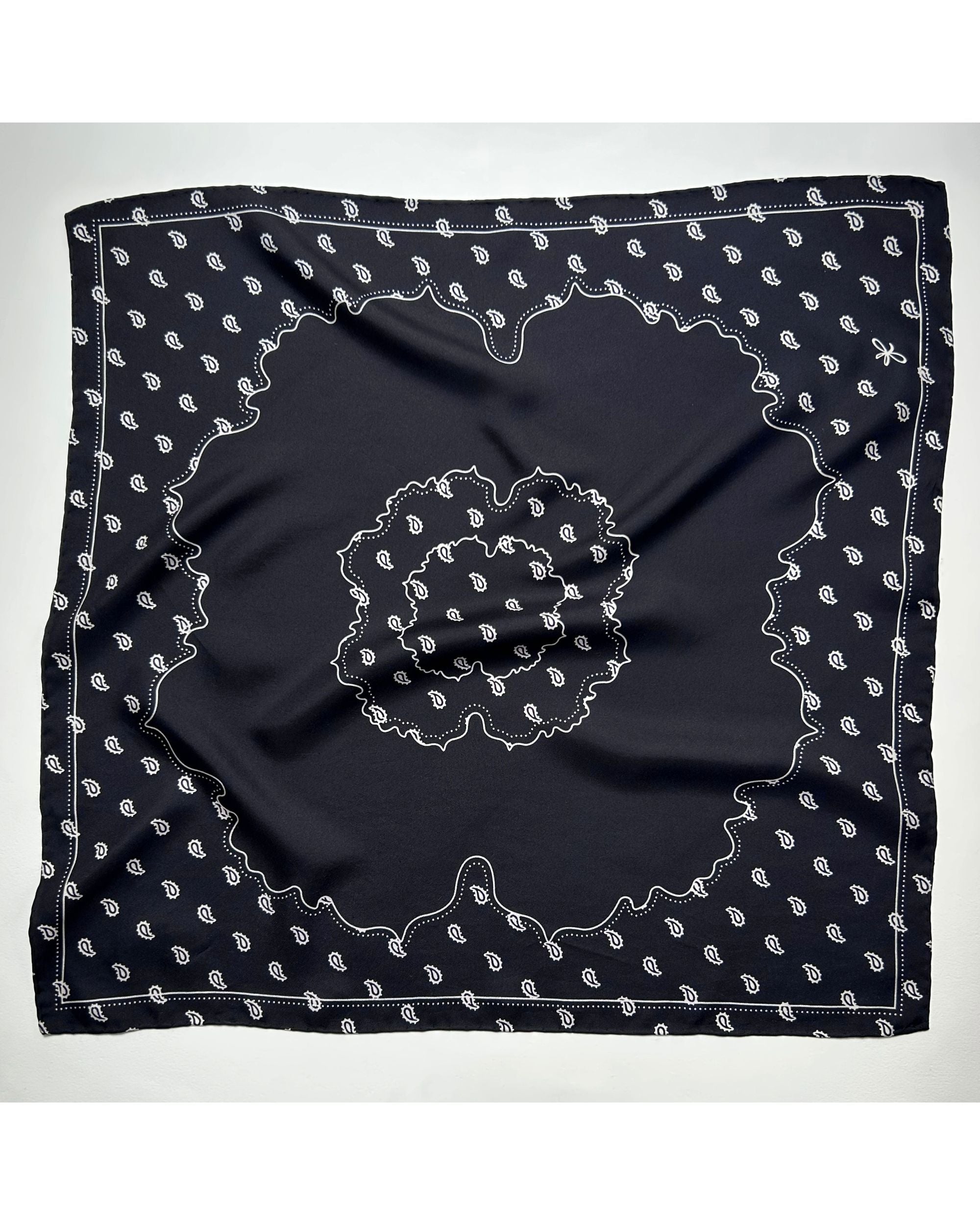 Square black silk scarf laid flat with central medallion design
