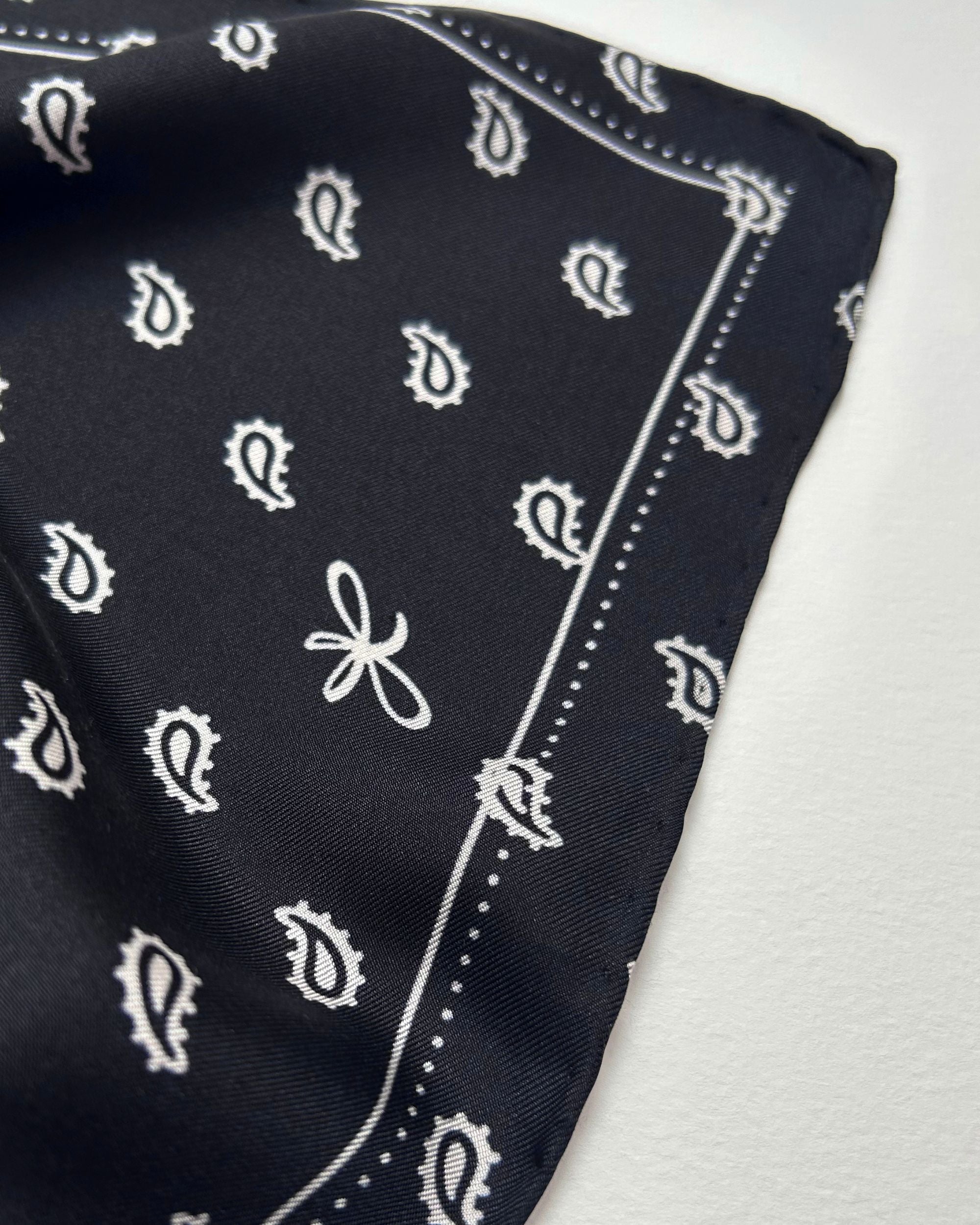 Close-up of black silk scarf with paisley and logo detail