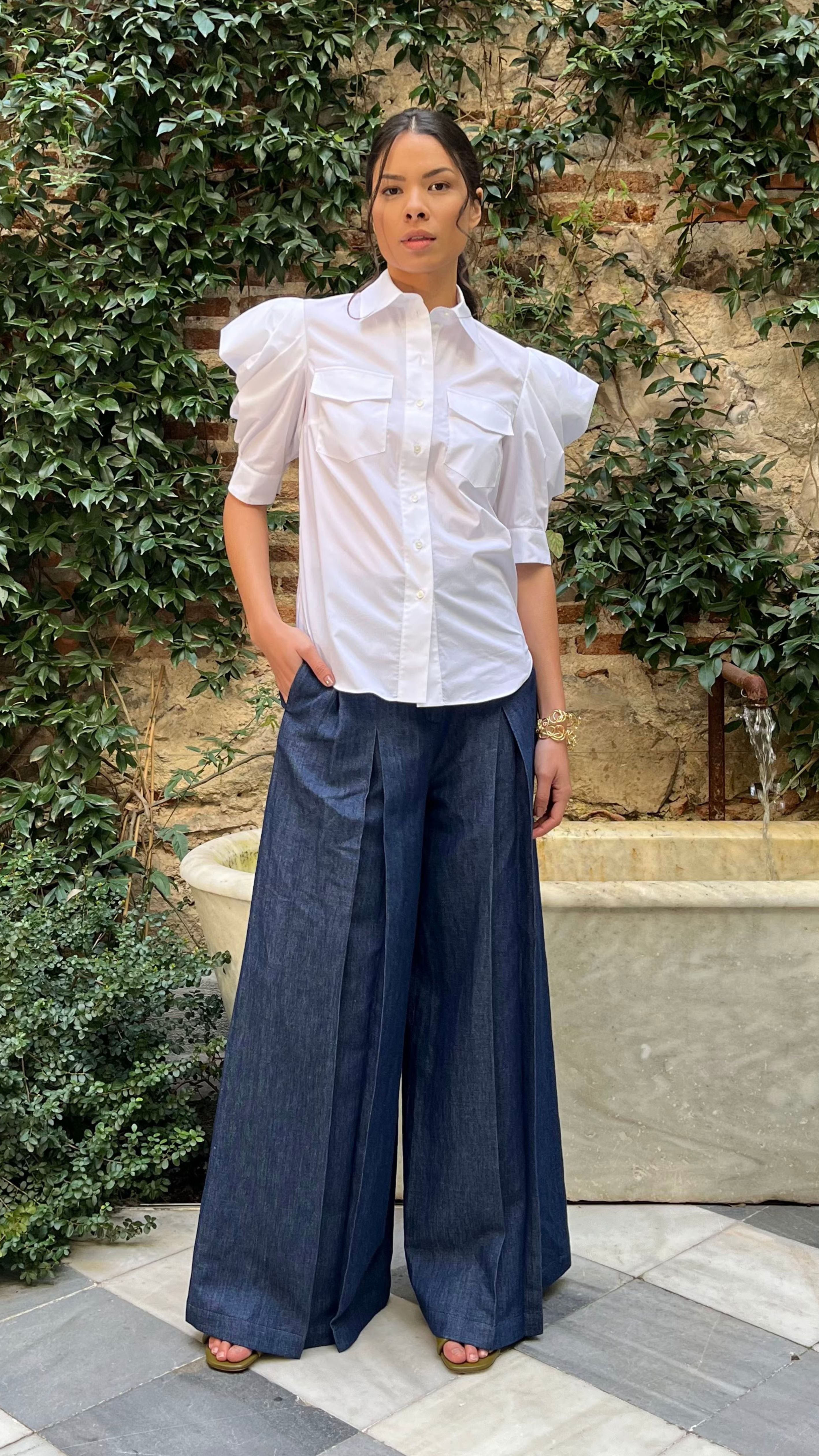 Rochas Paris Cotton Poplin Short Sleeved Shirt. A button up blouse in lightweight cotton it has two front pockets and puffed sleeves. Photo shown on model also wearing Rochas wide leg denim trousers.