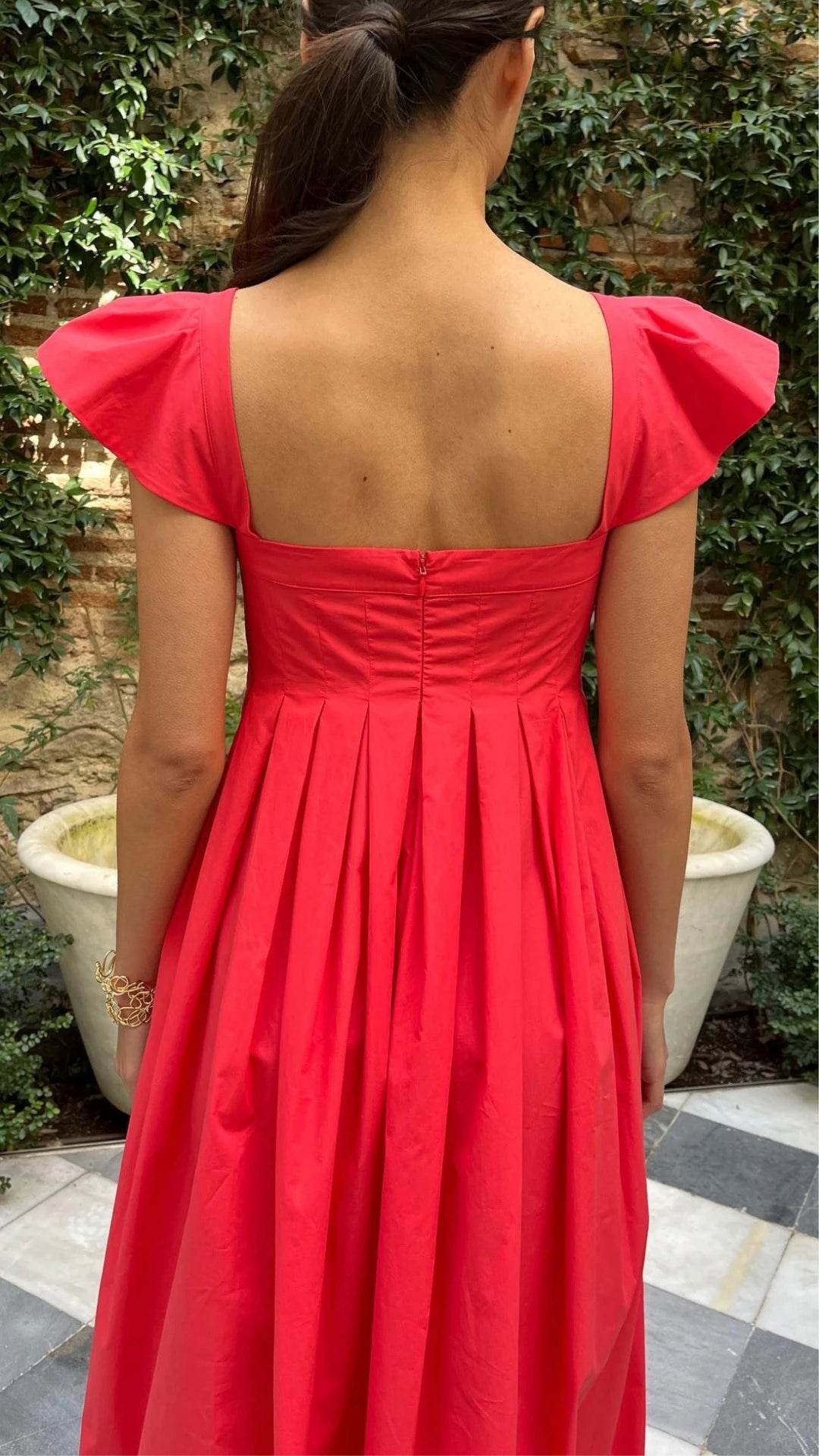 Rochas Paris Empire Waist Cotton Poplin Dress. Sweet with capped sleeves and a square neckline. The fitted body gives way to an a-line skirt. Red cotton poplin summer style. Shown on the model facing to the back and showing the hidden zipper detail..