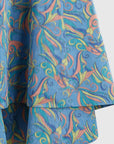Rochas Paris Sleeveless Cocoon Dress in blue abstract pattern with orange and yellow details. With a halter neck and open scooped back. Asymmetrical midi skirt. Unique dress for any occasion. Detail photo of material and pattern.