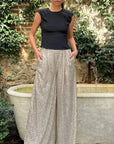 Rochas Paris Fashion High Waisted Sparkle Pants. Crafted in silver paillette sequins, they are tailored with a subtle front pleating and a fitted waist to create a slim, flattering silhouette. Shown on model facing front.