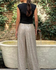 Rochas Paris Fashion High Waisted Sparkle Pants. Crafted in silver paillette sequins, they are tailored with a subtle front pleating and a fitted waist to create a slim, flattering silhouette. Photo of the model in the trousers from the back.