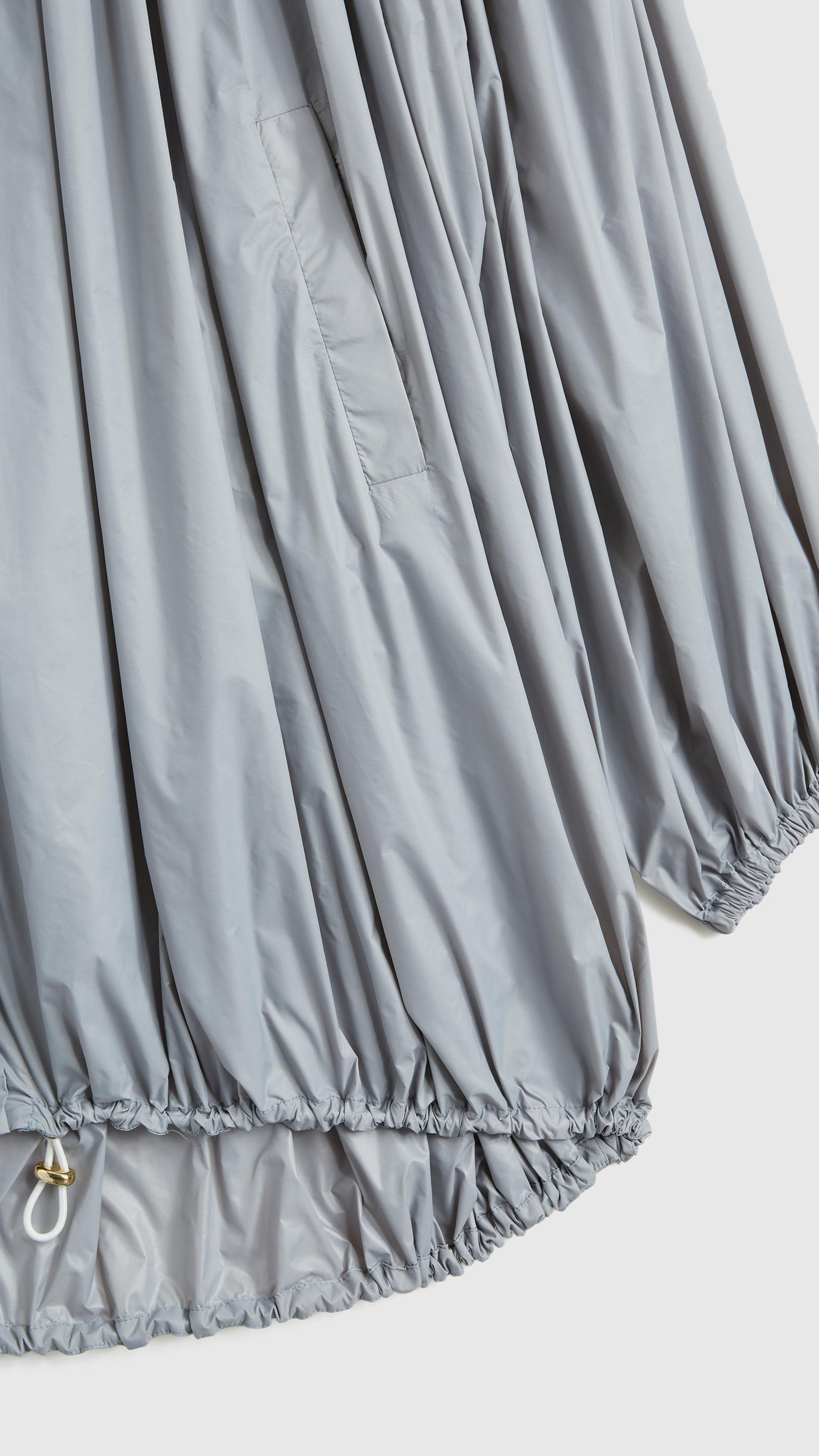 Rochas Paris Fashion Oversized Wind Jacket in a sky silver blue. Pleated draping across the front makes this elegant and luxurious outerwear jacket. Detail photo showing sleeve and drawstring hemline detail.