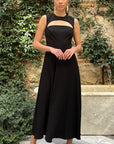 Roksanda Datura Dress. Black midi dress is crepe with front cut our panel and a line draped skirt. Midi length dress. Sleeveless. Open back with elegant tied bow at back nape neck. Shown on model facing front.