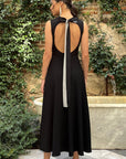 Roksanda Datura Dress. Black midi dress is crepe with front cut our panel and a line draped skirt. Midi length dress. Sleeveless. Open back with elegant tied bow at back nape neck. Shown on model facing back.
