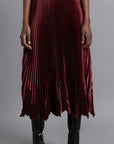 Thebe Magugu Chevron Pleated Skirt in a rich burgundy color. Fitted at the waist with straight pleats it falls into a double chevron pleat bottom. Long in length. It comes with a tie belt. Shown on model facing forward.